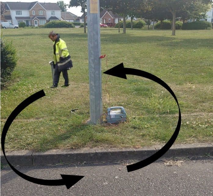 Operative circling a lighting column with the CAT while the Genny sits at its base — the search worked around the column, arrow overlay showing the path.