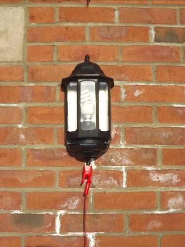 External wall lantern with a red crocodile clip on its supply — using the lighting circuit at a property.