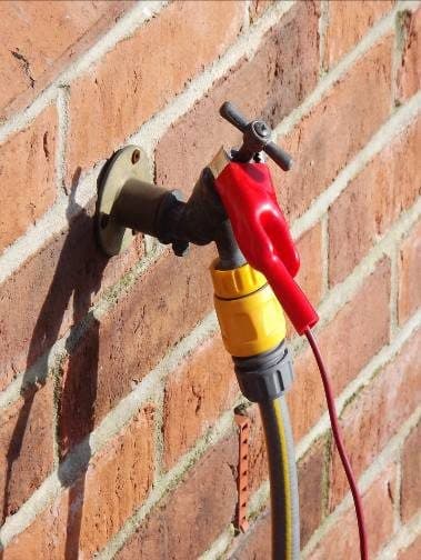 Red clip on an outside tap — using bonded metalwork as the connection point.