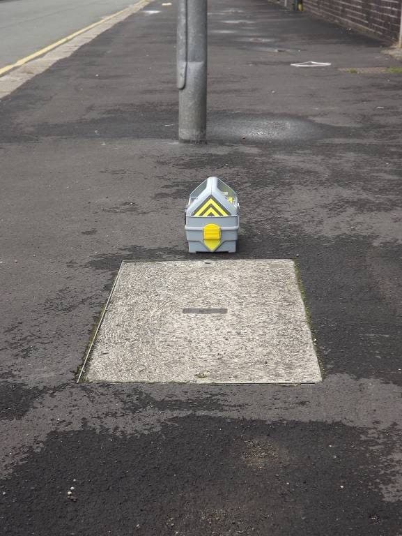 Genny stood upright on the footway in line with a chamber cover — induction position.
